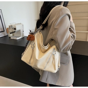 Detail of cream matte leather tote bag with star zipper and brown plush bear charm