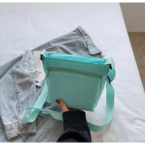 Detail of mint green nylon messenger bag with waterproof texture on white bedsheet