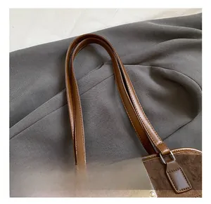 Close-up of brown suede tote bag with leather strap and square silver metal buckle detail