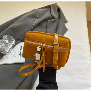 Close-up of yellow suede box bag with metal robot pendant and adjustable strap details