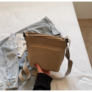 Detail of khaki nylon crossbody bag with zipper compartments and wide shoulder strap