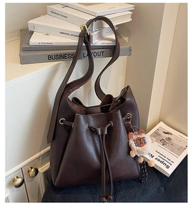 Detail of vintage dark brown PU leather bucket bag with cute plush bear charm