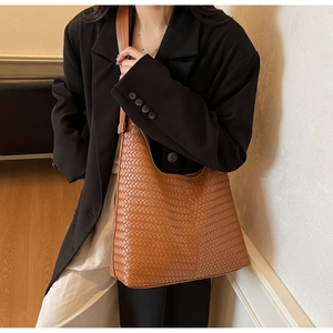 Gros plan d'un sac hobo marron en cuir tressé avec bandoulière large sur un modèle