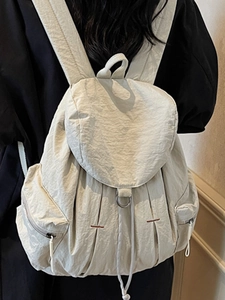 Mochila minimalista de nailon blanco crema con solapa y hebilla metálica sobre modelo