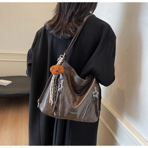Detail of dark brown vintage PU leather tote bag with two star zipper pockets and plush charm