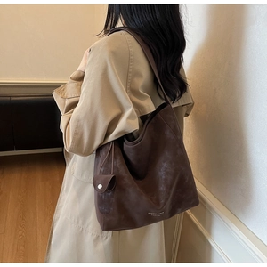 Détail d'un grand sac cabas vintage en cuir marron foncé avec logo de la marque