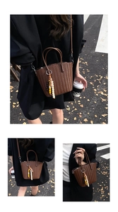 Close-up of brown woven bucket bag with beaded tassel charm and slim shoulder strap