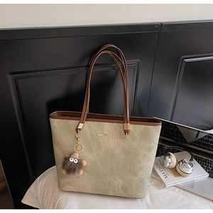Detail of grey marble texture tote bag with brown plush monster charm on its side