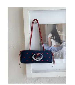 Dettaglio borsa blu navy a pois con pizzo a cuore e spalline in pelle sintetica rossa