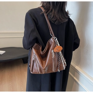 Detail of vintage brown PU leather tote bag with side metal zippers and plush dog charm