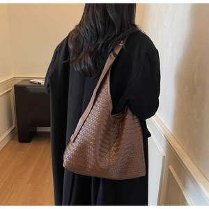 Détail de la texture tressée du sac cabas hobo marron foncé porté à l'épaule