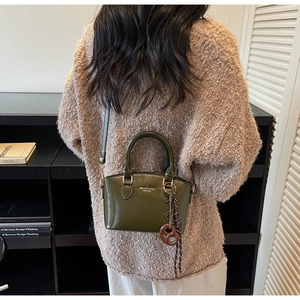 Detailed view of an olive green patent leather bag with a unique pretzel charm
