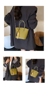 Detail view of woven green tote bag with multi-colored bead charm and detachable strap