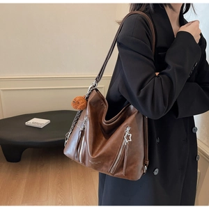 Detail view of brown vintage tote bag with star zippers and plush ball charm on a model