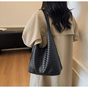 Détail du sac hobo tressé en cuir noir avec large bandoulière et texture sophistiquée