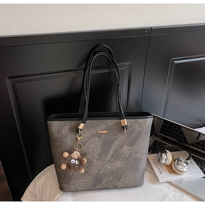 Chic grey tote bag featuring marble texture, gold metal detail, and a cute plush monster charm