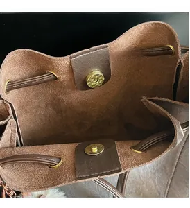 Detail view of brown vintage bucket bag showing gold magnetic closure and suede lining