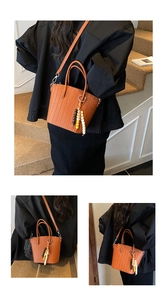 Detail of brown woven bucket bag with beaded charm accessory and detachable shoulder strap