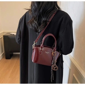 Detailed view of deep red glossy leather handbag with gold hardware and silk scarf