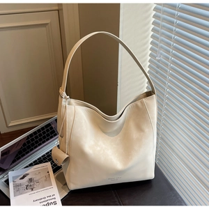 Détail d'un grand sac Hobo crème avec une mini pochette latérale sur une surface en cuir