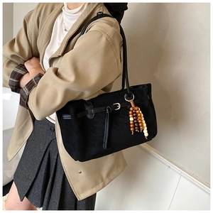 Dettaglio della borsa tote in pelle scamosciata nera con nappina di perline di legno