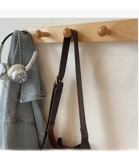 Detail of wooden wall-mounted hook rack holding a jacket, headphones, and bag