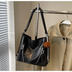 Detailed view of black PU tote bag with teddy bear charm and star-shaped zippers