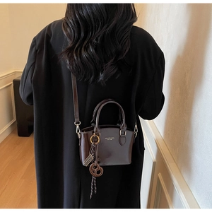Detail of a chocolate brown structured tote with gold hardware and brand logo