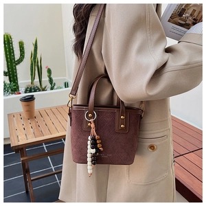Détail du sac seau en daim marron avec motifs matelassés et breloques en perles colorées