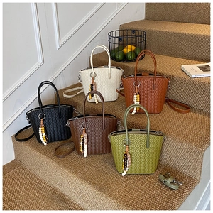 Detail of woven tote bags in five stylish colors with beaded charms on stairs