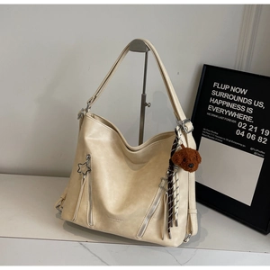 Detail of milk tea leather tote featuring star zipper pulls and plush bear charm