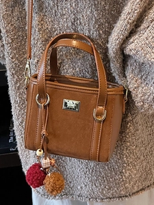 Retro brown leather and suede bucket bag with long strap and plush charm on casual outfit