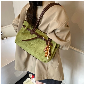 Dettaglio della borsa tote in pelle scamosciata verde con cinturino marrone e nappa etnica