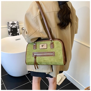 Detail view of vintage green suede shoulder bag with brown leather trim and tassel on a model