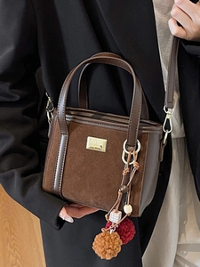 Fashionable dark brown square bucket bag with gold logo and colorful fur ball charm accessory