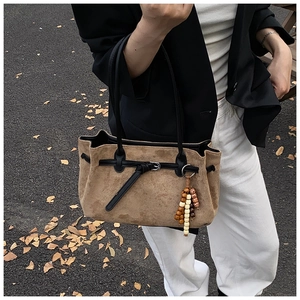 Dettaglio della borsa tote in pelle scamosciata marrone con cinturini neri e ciondolo