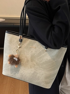 Chic grey-green marble textured tote bag with black trim and plush monster charm