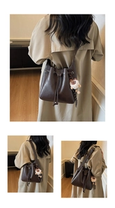 Close-up of dark brown leather bucket bag with drawstring and plush sheep pendant