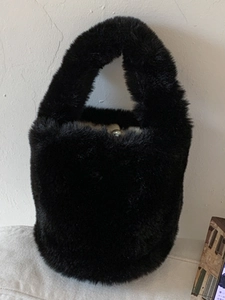 Minimalist black faux fur bucket bag with a soft plush texture and matching top handle
