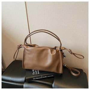 Detailed view of dark brown pebbled leather handbag with side knot and adjustable strap