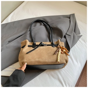 Dettaglio ravvicinato della borsa tote in pelle scamosciata marrone con manici neri