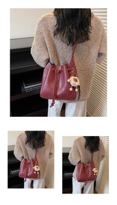 Detail of burgundy leather bucket bag with drawstring closure and white sheep charm