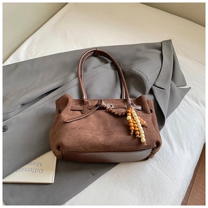 Dettaglio della borsa tote in pelle scamosciata marrone con manici in pelle e perline