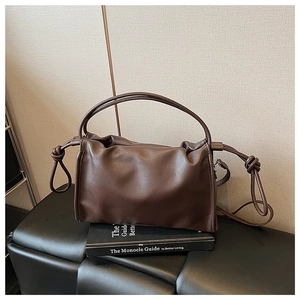 Detail of dark brown leather handbag with unique pleated closure and decorative knots