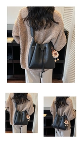 Detail of black drawstring bucket bag with leather texture and cute plush bear charm