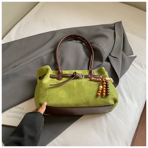 Dettaglio della borsa tote in pelle scamosciata verde con cinturini in pelle marrone