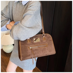 Detail of dark brown suede shoulder bag with metal zipper and leather tassels