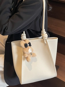 Minimalist beige leather tote bag for women with cute plush bear charm on shoulder strap