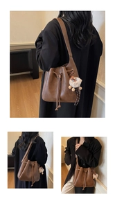 Detail view of brown vintage bucket bag with drawstring closure and plush sheep charm
