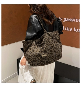Detailed view of leopard print canvas tote bag carried over shoulder by a model